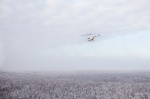 Хмурое небо и заснеженный лес ― будто кадры из черно-белого фильма, просматриваемого через окно вертолета