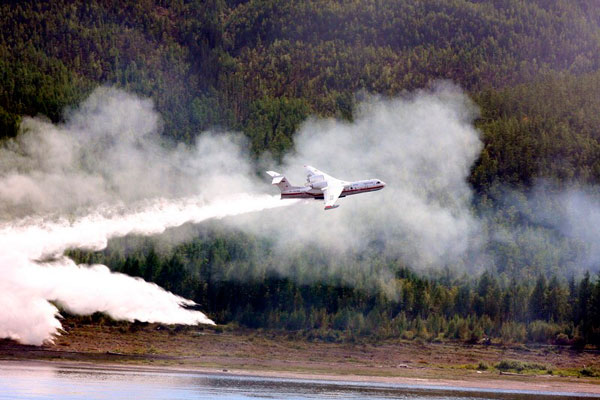 Самолет сбрасывает воду на горящую лесную полосу