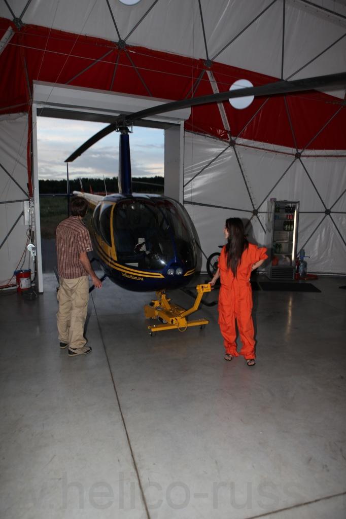 девушка вкатывает вертолет в ангар при помощи helimover.JPG